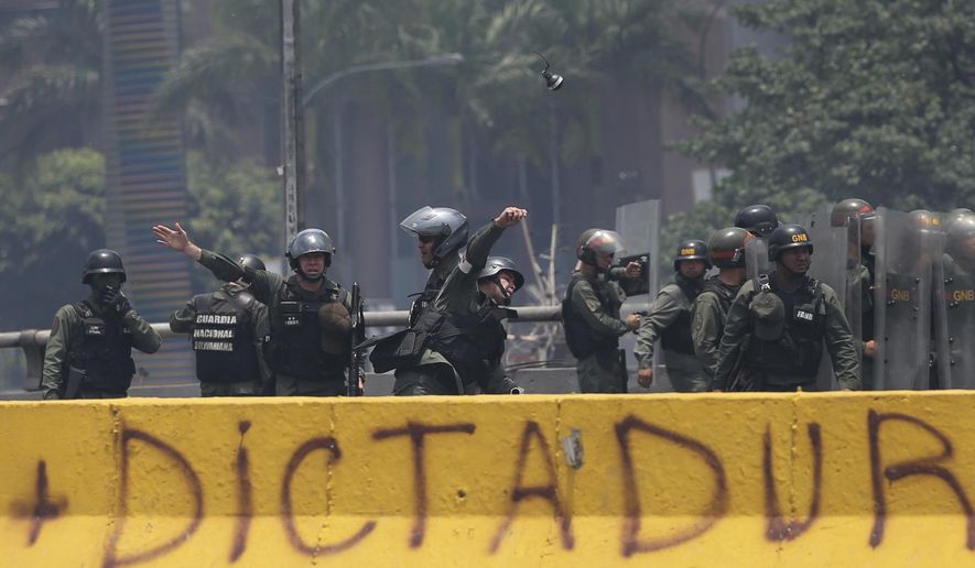 A Venezuelan Bolivarian National Guard officer throws a tear gas grenade towards demonstrators during a protest in Caracas, Venezuela, Monday, April 10, 2017. Thousands of people in Venezuela&#x27;s capital are protesting against the government of President Nicolas Maduro, demanding new elections and vowing to stay in the streets during the usually quiet Easter Week.(AP Photo/Fernando Llano)