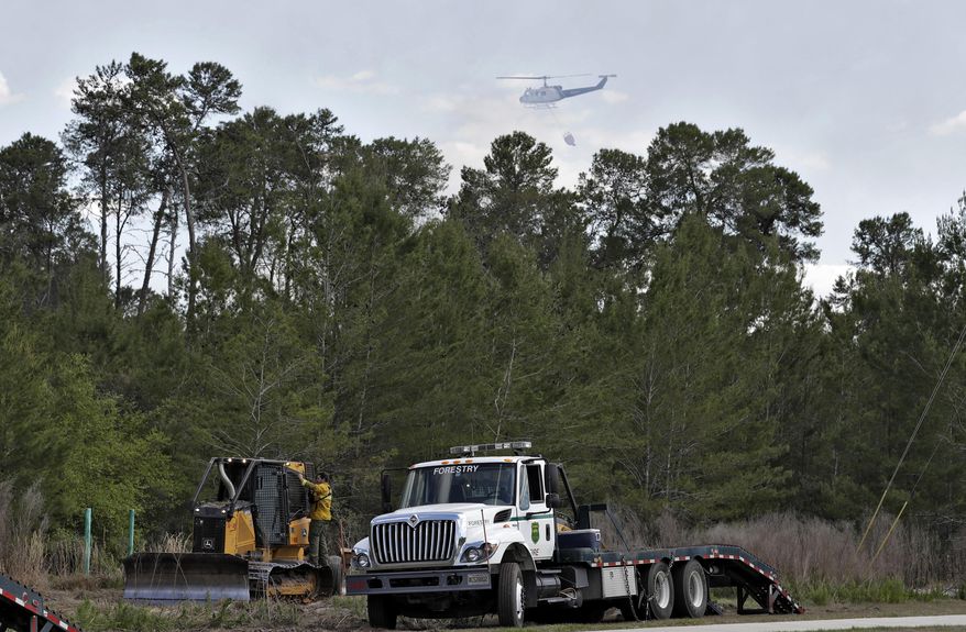 A Florida Division of Forestry helicopter drops a bucket of water on a wildfire Tuesday, April 11, 2017, in Hudson, Fla. Florida Gov. Rick Scott has declared a state of emergency as more than 100 wildfires actively burn statewide. (AP Photo/Chris O'Meara)