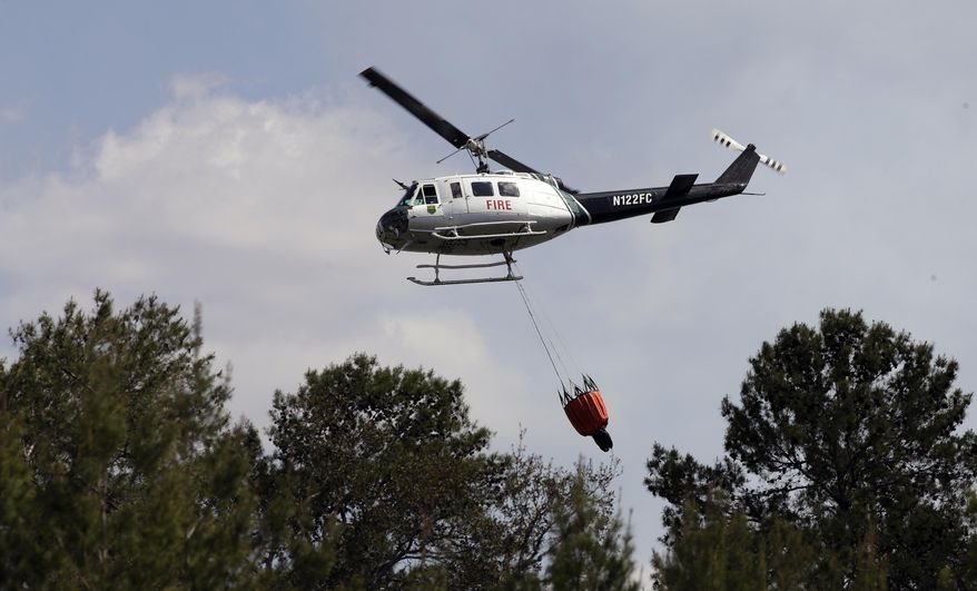 A Florida Division of Forestry helicopter drops a bucket of water on a wildfire Tuesday, April 11, 2017, in Hudson, Fla. Florida Gov. Rick Scott has declared a state of emergency as more than 100 wildfires actively burn statewide. (AP Photo/Chris O'Meara)