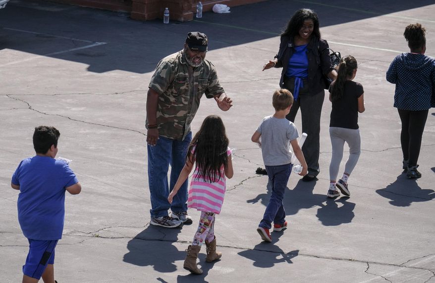School staff greet students at North Park Elementary School at Cajon High School, Monday, April 10, 2017, in San Bernardino, Calif., after a deadly shooting occurred at the elementary school. (AP Photo/Ringo H.W. Chiu)