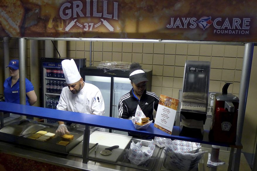 People work at the Grilli sandwich counter at the Rogers Centre in Toronto on Wednesday, April 12, 2017. The Jays are running a "Fire up the Grilli" promotion in April — which is also National Grilled Cheese Month — with a Jason Grilli-designed sandwich on sale at Section 244 of the Rogers Centre. A portion of the proceeds go to the Jays Care Foundation. (Neil Davidson/The Canadian Press via AP)