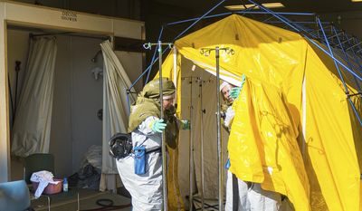 FILE - In this Oct. 21, 2016 file photo emergency workers clean various items inside a decontamination tent at Mosaic Life Care, in Atchison, Kan. Federal investigators say Human error and problems with design and labeling led to the release of a large chemical cloud over the city that sent more than 140 people to the hospital last year. The chemical release from MGP Ingredients in Atchison, occurred when a delivery truck driver inadvertently unloaded sulfuric acid into a tank that contained sodium hypochlorite. (Dougal Brownlie/The St. Joseph News-Press via AP File)