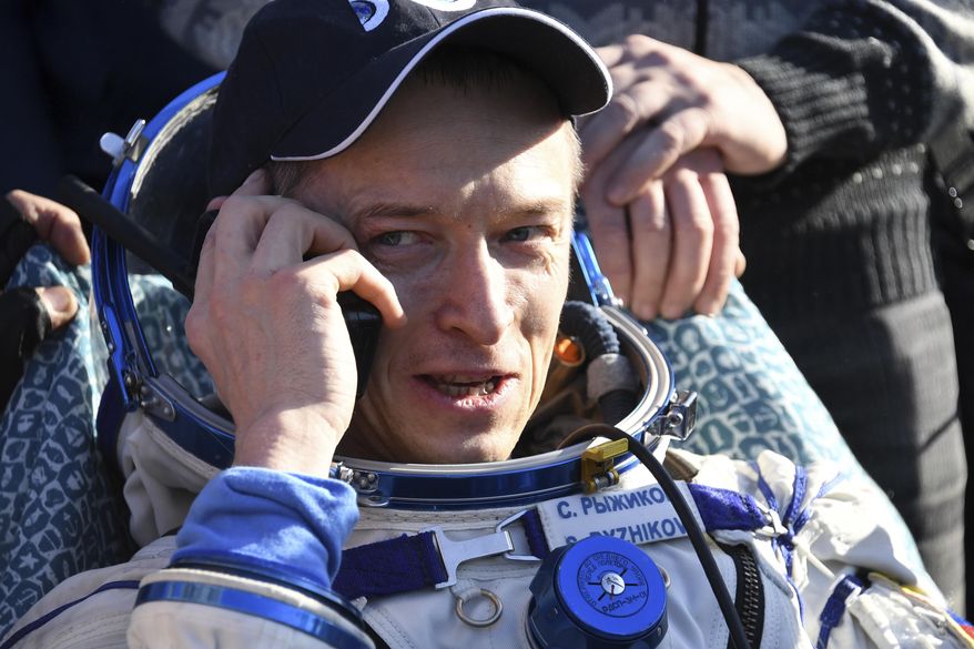 Russian cosmonaut Sergey Ryzhikov uses a sat phone shortly after landing near Dzhezkazgan, Kazakhstan Monday, April 10, 2017, on the treeless Central Asian steppes Russia's Soyuz MS-02 space capsule carrying the International Space Station (ISS) crew of Andrei Borisenko and Sergey Ryzhykov of Russia and NASA astronaut Robert Shane Kimbrough landed in a remote area in Kazakhstan. (Kirill Kudryavtsev/Pool photo via AP)