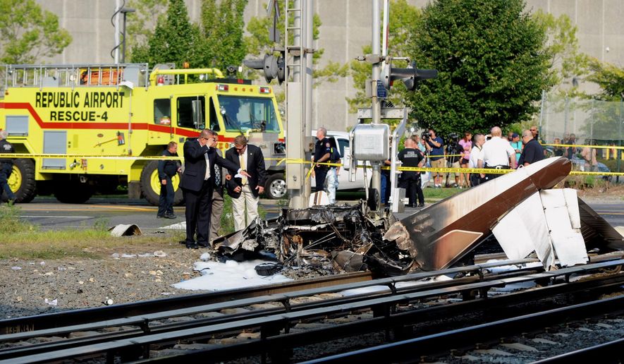 FILE- In this Aug. 16, 2015 file photo, investigators examine the scene where one person died and another was injured in the crash of a single-engine plane on Long Island Rail Road tracks on the line between Bethpage and Hicksville, NY. As a result of this crash, the Federal Aviation Administration now regularly check the accuracy of its radar video maps after an air traffic controller directed the pilot with engine trouble to a closed airport moments before the plane went down. (James Carbone/Newsday via AP, File)