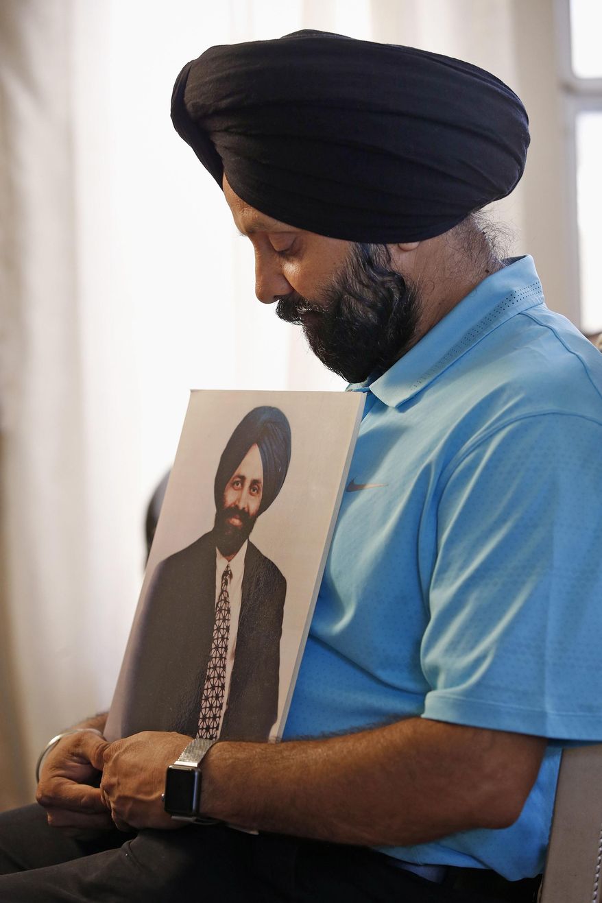 FILE - In this Aug. 19, 2016 file photo, Rana Singh Sodhi, 49, holds a photograph in Gilbert, Ariz. of his murdered brother, Balbir Singh Sodhi, who was murdered in the days after the Sept. 11 terrorist attacks by a man who said he wanted to kill Muslims. The Sikh religion was founded in India to promote religious freedom, gender equality and opportunity for all. Yet their beards and turbans make American Sikhs easy targets for the angry and uninformed who believe they are Muslims. (AP Photo/Ross D. Franklin, File)