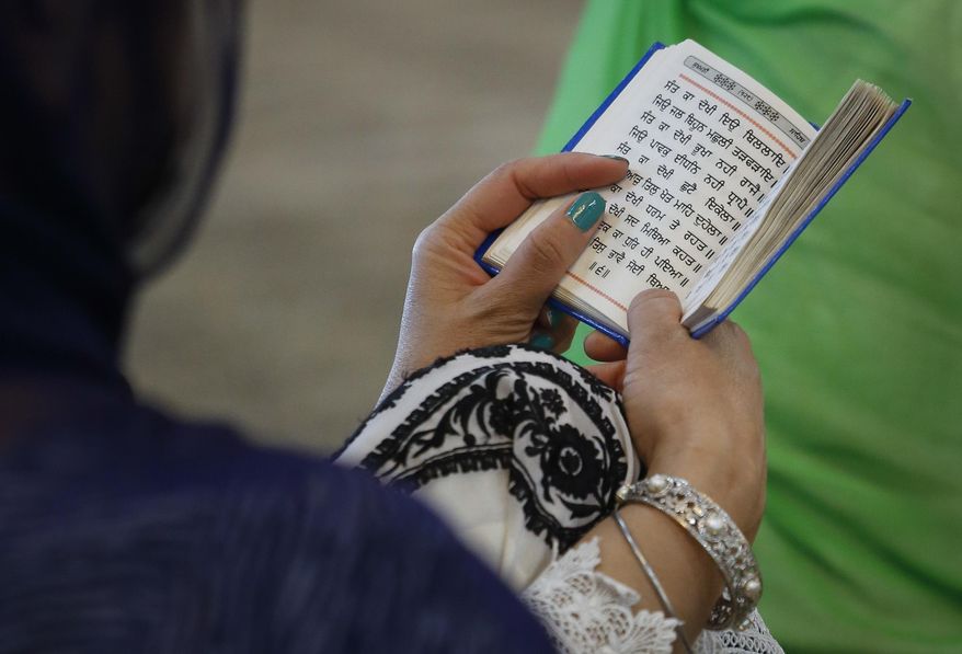 In this April 9, 2017 photo, a Sikh woman reads from her holy book during a prayer recital at the Guru Nanak Darbar house of worship, in Hicksville, N.Y. Women and men share equal roles in the temple where Sikhs come together for worship and to serve community meals free for anyone regardless of faith, religion or background. (AP Photo/Bebeto Matthews)