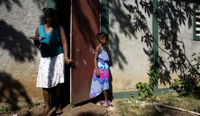 In this Aug. 17, 2016 photo, Marie-Ange Haitis, 40, stands with her daughter, Samantha, at their home in Leogane, Haiti. Haitis says she met a Sri Lankan commander in December 2006 and he soon began making nighttime visits to her house. “By January, we had had sex,” she said. “It wasn’t rape, but it wasn’t exactly consensual, either. I felt like I didn’t have a choice.” Haitis says Samantha has started asking more questions about her father. (AP Photo/Dieu Nalio Chery)
