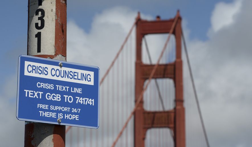 A suicide prevention sign is posted at the Golden Gate Bridge, Thursday, April 13, 2017, in San Francisco. Local officials gathered Thursday at the orange-red span to mark the beginning of work to line both sides of the bridge with steel netting. (Alan Dep/Marin Independent Journal via AP)