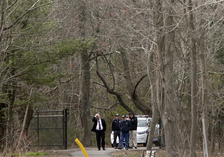 Crime scene investigators and other emergency personnel walk near a crime scene in Central Islip, N.Y., Thursday, April 13, 2017. The victims, who were not immediately identified, were found in a wooded area near a recreation center in the suburban area, east of New York City. (AP Photo/Seth Wenig)
