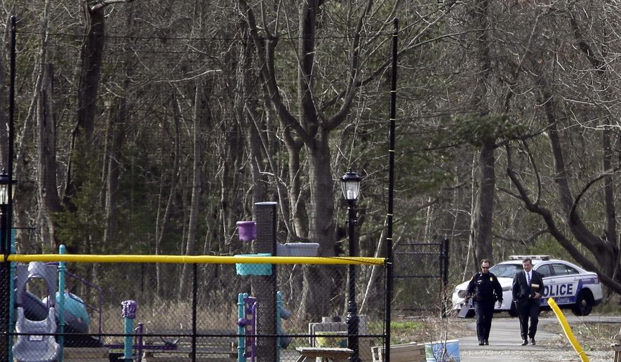 Emergency personnel walk near a crime scene where four bodies were found in Central Islip, N.Y., Thursday, April 13, 2017. The victims, who were not immediately identified, were found in a wooded area near a recreation center in the suburban area, east of New York City. (AP Photo/Seth Wenig)