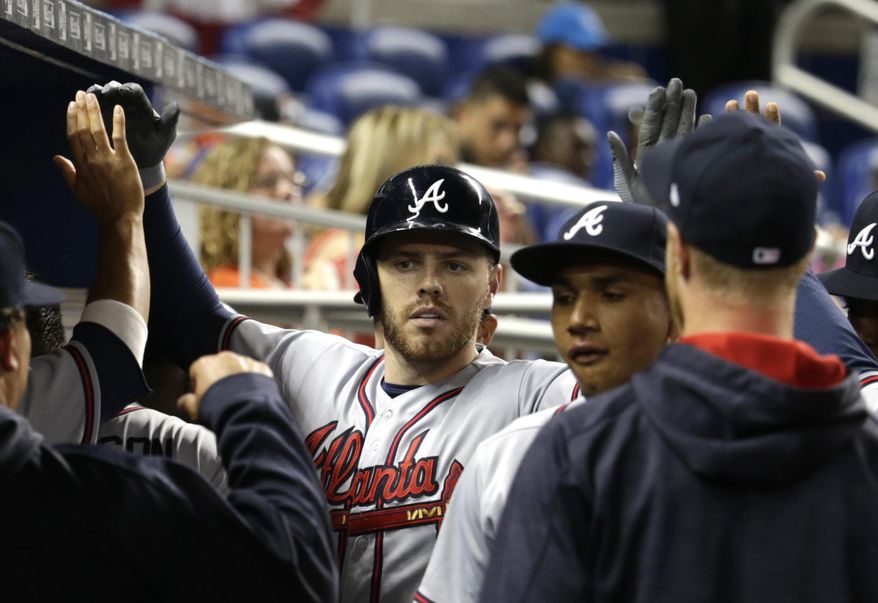 Atlanta Braves' Freddie Freeman is met in the dugout after hitting solo home run during the fourth inning of a baseball game against the Miami Marlins, Wednesday, April 12, 2017, in Miami. (AP Photo/Lynne Sladky)