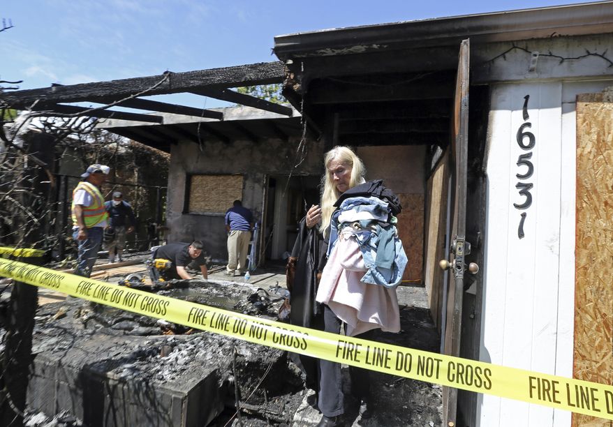 Gunilla Persson, star of the Swedish television reality show "Svenska Hollywoodfruar," or "Swedish Hollywood Wives" takes clothing so she can move into a hotel following a predawn fire that severely damaged her home and a neighbor's in the Pacific Palisades area of Los Angeles Thursday, April 13, 2017. (AP Photo/Reed Saxon)
