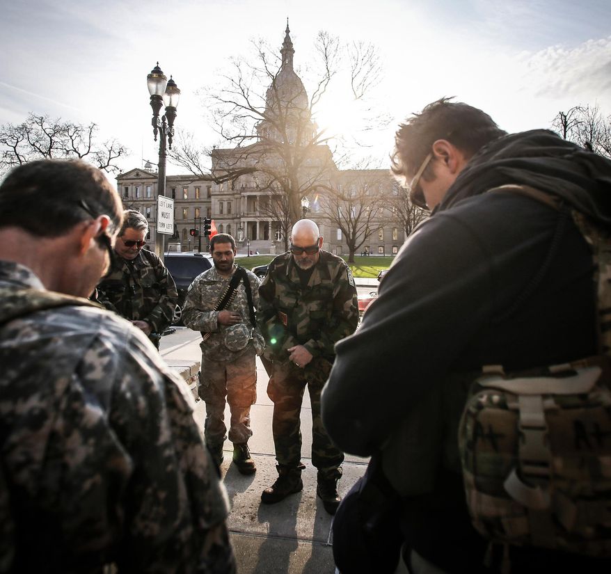Volunteer Michigan Militia Chaplain Ed "Bo" Bowman prays with fellow members for peace and the safety of all, Wednesday, April 12, 2017, outside of City Hall. Inside, a special Lansing City Council meeting on Lansing's short-lived sanctuary city status was being held. Citizens from both sides spoke for nearly three hours before the council voted 5-2 to remove the 'Sanctuary City' designation. (Matthew Dae Smith/Lansing State Journal via AP)