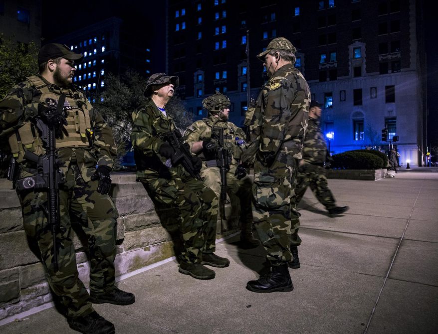 About 16 armed Michigan Militia members post themselves outside Lansing City Hall Wednesday, April 12, 2017, while inside, the Lansing City Council listens to concerned citizens both for and against Lansing's 'Sanctuary City' status. The board voted 5-2 to rescind the short-lived sanctuary city declaration. A volunteer Militia member stated he was there protecting people's free speech regardless of their stance on issues. (Matthew Dae Smith/Lansing State Journal via AP)