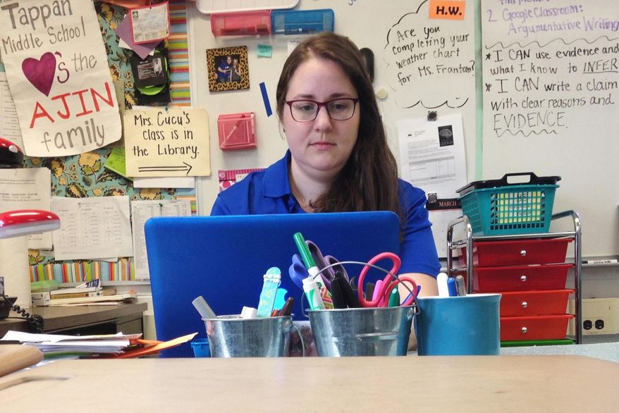 In this Monday, April 3, 2017, photo, Samantha Cucu types on a laptop inside her classroom at Tappan Middle School in Ann Arbor, Mich. The English and language arts teacher is among a number of educators nationwide who purchase lessons from other teachers online. One site, Teachers Pay Teachers, said it has helped make millionaires out of some of its contributors since launching about 10 years ago. (AP Photo/Mike Householder)