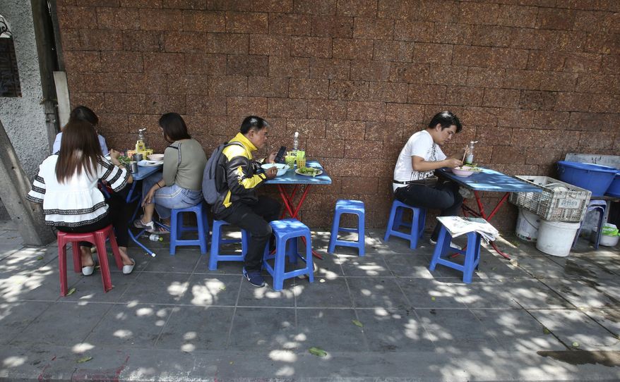 In this April 7, 2017 photo, people eat noodles at a street food stall during their lunch on Thonglor road in Bangkok, Thailand. Officials see street food as an illegal nuisance and have warned hawkers in Thonglor to clear out by April 17. Efforts by authorities in military-ruled Thailand to impose order on the chaotic capital city have a fresh target: cheap and tasty pad thai. The latest crackdown by Bangkok city officials is going after the vendors whose carts selling everything from Thailand’s signature noodles to spicy tom yum goong soup have become institutions on the capital’s hot and humid sidewalks. (AP Photo/Sakchai Lalit)