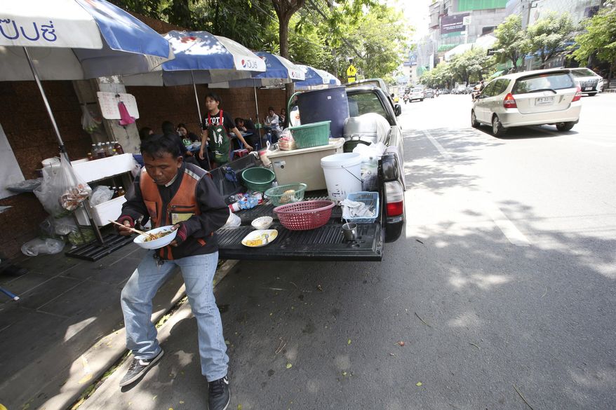 In this April 7, 2017 photo, a motorcycle taxi driver eats noodles at a street food stall during his lunch on Thonglor road in Bangkok, Thailand. Officials see street food as an illegal nuisance and have warned hawkers in Thonglor to clear out by April 17. Efforts by authorities in military-ruled Thailand to impose order on the chaotic capital city have a fresh target: cheap and tasty pad thai. The latest crackdown by Bangkok city officials is going after the vendors whose carts selling everything from Thailand’s signature noodles to spicy tom yum goong soup have become institutions on the capital’s hot and humid sidewalks. (AP Photo/Sakchai Lalit)