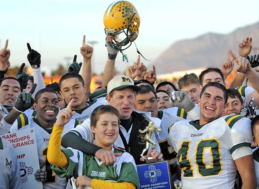 FILE--In this Dec 4, 2010, file photo, Mayfield head coach Michael Bradley, center right, celebrates with his layers after winning the state 5A high school football championship game against Manzano in Albuquerque, N.M. Athletics are losing out in the competition for limited dollars as one of the nation's largest school districts prepares for an anticipated 2 percent cut in state funding. (Jim Thompson/The Albuquerque Journal via AP, File)