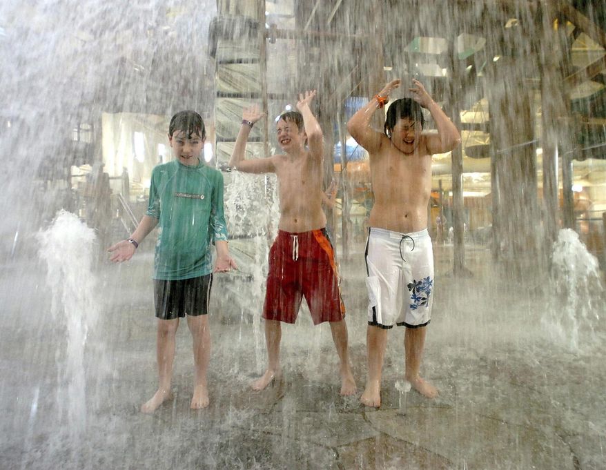 FILE – In this Oct. 26, 2005, file photo, Collin Bevan, left, Keith Casares, center, and Jared Kubalak, right, all from Cresco, Pa., play under a rush of water at Great Wolf Lodge in Scotrun, Pa. The picturesque Pocono Mountains region is re-emerging as a haven for family fun, much as it was in the 1950s, with the popularity of indoor water park resorts that provide year-round entertainment. (David Kidwell/Pocono Record via AP, File)