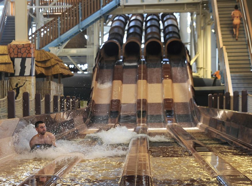 FILE – In this March 8, 2017, file photo, Mark Pash, left, of Baltimore, and Liz Haibach, center, of Philadelphia, race down one of the water slides in the Kalahari Resort and Convention Center's indoor water park in Pocono Manor, Pa. The picturesque Pocono Mountains region is re-emerging as a haven for family fun, much as it was in the 1950s, with the popularity of indoor water park resorts that provide year-round entertainment. (Keith R. Stevenson/Pocono Record via AP, File)