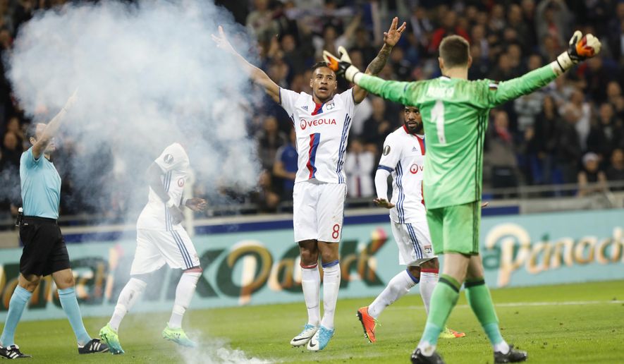 Smoke from something thrown onto the pitch as Lyon&#39;s Corentin Tolisso, center, celebrates scoring a goal during the Europa League quarterfinal soccer match between Lyon and Besiktas, in Decines, near Lyon, central France, Thursday, April 13, 2017. (AP Photo/Laurent Cipriani)