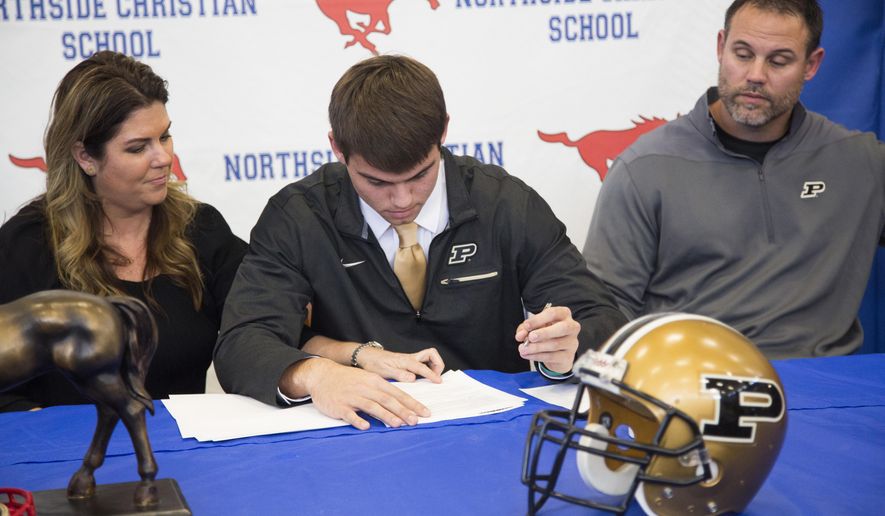 FILE - In this Feb. 1, 2017, file photo, Northside Christian High School quarterback Griffin Alstott gets help from his mom, Nicole, on where to sign as he commits to Purdue University at Northside Christian High School on National Signing Day in St. Petersburg, Fla. At right is his father, Mike Alstott, who used to play for the Tampa Bay Buccaneers. The NCAA has voted to allow high school football players to sign with colleges as early as December, make early official visits and put a two-year waiting period on Bowl Subdivision teams from hiring people close to a recruit. If approved by the Board of Governors on April 26, the signing period change would take effect Aug. 1. (Eve Edelheit/The Tampa Bay Times via AP, File)