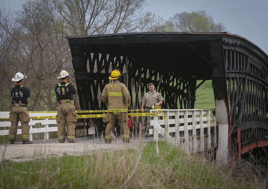 Madison County officials investigate a fire that destroyed the structure of the Cedar Covered Bridge, north of Winterset, Iowa, on Saturday, April 15, 2017. The fire was reported around 6 a.m., and was fully engulfed when fire crews arrived. (Bryon Houlgrave/The Des Moines Register via AP)