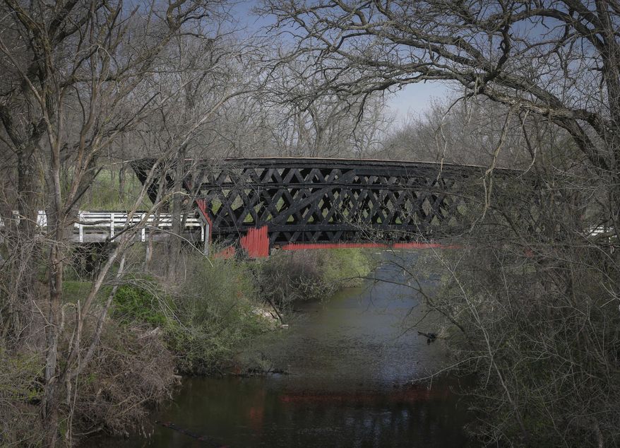 Madison County officials investigate a fire that destroyed the structure of the Cedar Covered Bridge, north of Winterset, Iowa, on Saturday, April 15, 2017. The fire was reported around 6 a.m., and was fully engulfed when fire crews arrived. (Bryon Houlgrave/The Des Moines Register via AP)