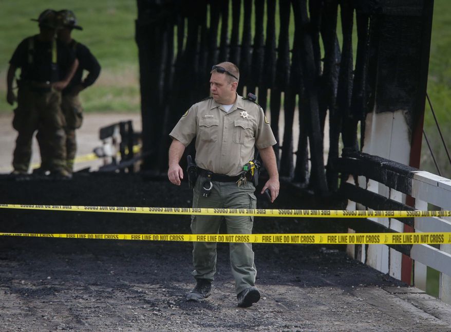 Madison County officials investigate a fire that destroyed the structure of the Cedar Covered Bridge, north of Winterset, Iowa, on Saturday, April 15, 2017. The fire was reported around 6 a.m., and was fully engulfed when fire crews arrived. (Bryon Houlgrave/The Des Moines Register via AP)