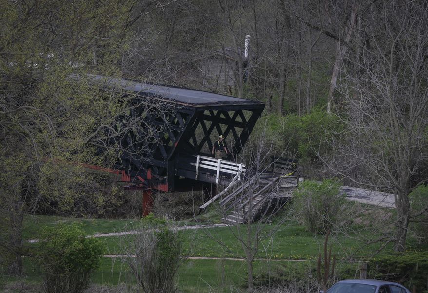 Madison County officials investigate a fire that destroyed the structure of the Cedar Covered Bridge, north of Winterset, Iowa, on Saturday, April 15, 2017. The fire was reported around 6 a.m., and was fully engulfed when fire crews arrived. (Bryon Houlgrave/The Des Moines Register via AP)
