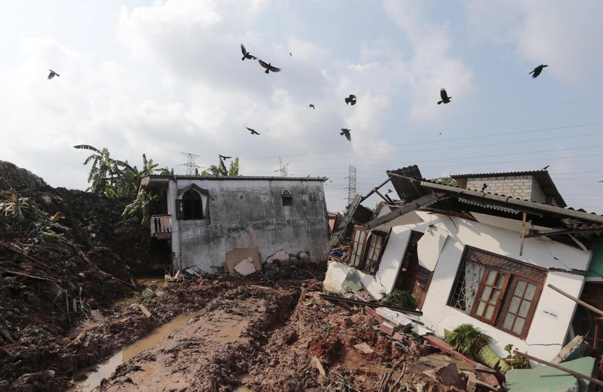 Crows fly over a row of houses buried by a collapse of a garbage dump in Meetotamulla, on the outskirts of Colombo, Sri Lanka, Saturday, April 15, 2017. A part of the garbage dump that had been used in recent years to dump the waste from capital Colombo collapsed destroying houses, according to local media reports. (AP Photo/Eranga Jayawardena)