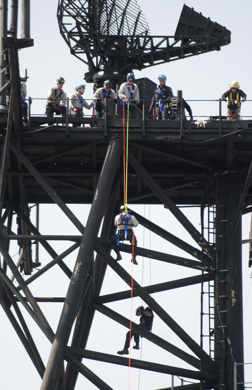 In this Thursday, April 13, 2017 photo, firefighters repel from an upper deck of the Battleship New Jersey as they take part in NSR Solutions LLC and Med-Tech's Confined Space Training classes aboard the battleship at the Battleship New Jersey Memorial and Museum, in Camden, N.J. (Chris LaChall /Camden Courier-Post via AP)