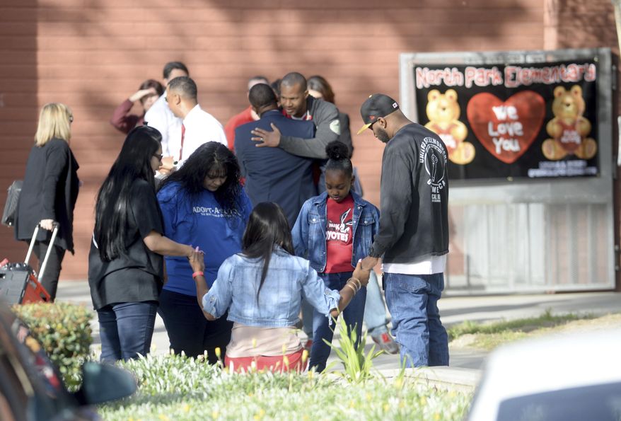 Anelina Perez, left in black shirt, and Marie Cabrera, blue shirt, pray with a family before the start of school Monday, April 17, 2017 at North Park Elementary in San Bernardino, Calif. Students returned to campus a week after Cedric Anderson, 53, of Riverside, entered the campus with a gun, killing his estranged wife Karen Elaine Smith, 53, student Jonathan Martinez, 8, and wounding student Nolan Brandy, 8, before turning the gun on himself. (John Valenzuela /Los Angeles Daily News via AP)