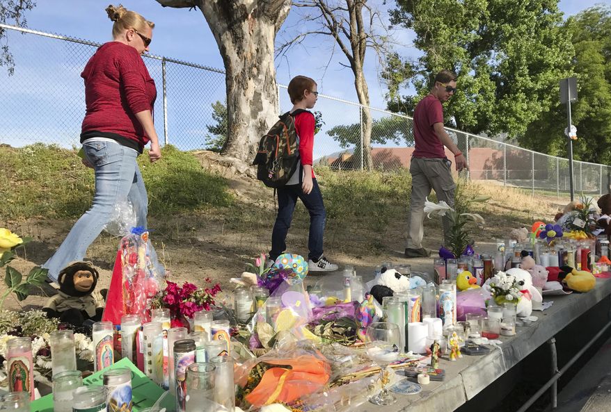 North Park Elementary student Jeremy Muschell, 9, center, walks to school with his mother Jane Muschell, left, and brother Jacob Parsons, Monday, April 17, 2017, in San Bernardino, Calif. Students returned to school a week after Cedric Anderson, 53, of Riverside, entered the campus with a gun, killing his estranged wife Karen Elaine Smith, 53, student Jonathan Martinez, 8, and wounding student Nolan Brandy, 9, before turning the gun on himself. (John Valenzuela /Los Angeles Daily News via AP)