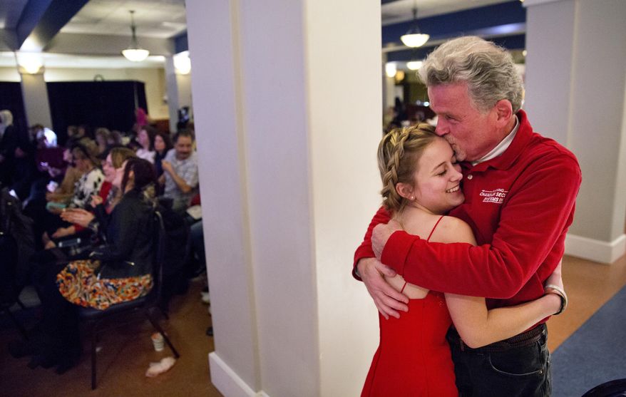 ADVANCE FOR USE WEDNESDAY, APRIL 19, 2017 AND THEREAFTER-Richard Rodrigue, right, embraces his daughter Stephanie, 17, after she walked the runway in her high school's pre-prom fashion show in Lewiston, Maine, Thursday, March 16, 2017. Rodrigue is proud his daughter is part of a diverse school whose students speak dozens of languages, and hail from dozens of nations. Though he is conflicted; "There's got to be a point in time when you have to say, 'whoa, let's get the working people back up, let's bring the money in.' But they keep coming, keep coming," Rodrigue said. “I guess it just boils down to: What’s enough? Is that wrong? Am I wrong? Am I bad? That’s how I feel.” (AP Photo/David Goldman)