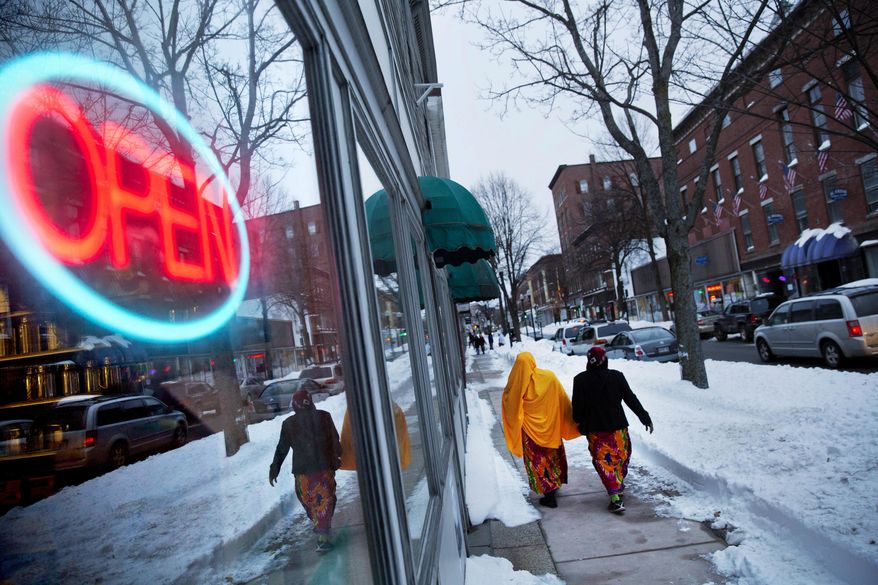 ADVANCE FOR USE WEDNESDAY, APRIL 19, 2017 AND THEREAFTER-Women wearing traditional muslim head coverings walk past one of the many stores downtown owned by African refugees who have settled in Lewiston, Maine, Friday, March 17, 2017. The refugees saw possibility in Lewiston's decay. Word spread quickly and friends and families followed, by the hundreds. The town morphed in a matter of months into a laboratory for what happens when demographics and culture suddenly shift. (AP Photo/David Goldman)