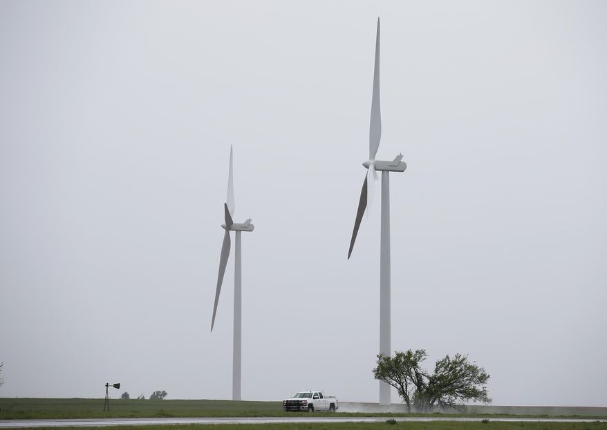 In this Thursday, April 13, 2017 photo, a truck drives by wind turbines near Okarche, Okla. Gov. Mary Fallin is expected to sign legislation Monday, April 17, that rolls back a 10-year tax credit for electricity generated by zero-emission facilities, an incentive for wind power generators as well as geothermal, solar and hydropower producers that’s been in place since 2003. (AP Photo/Sue Ogrocki)