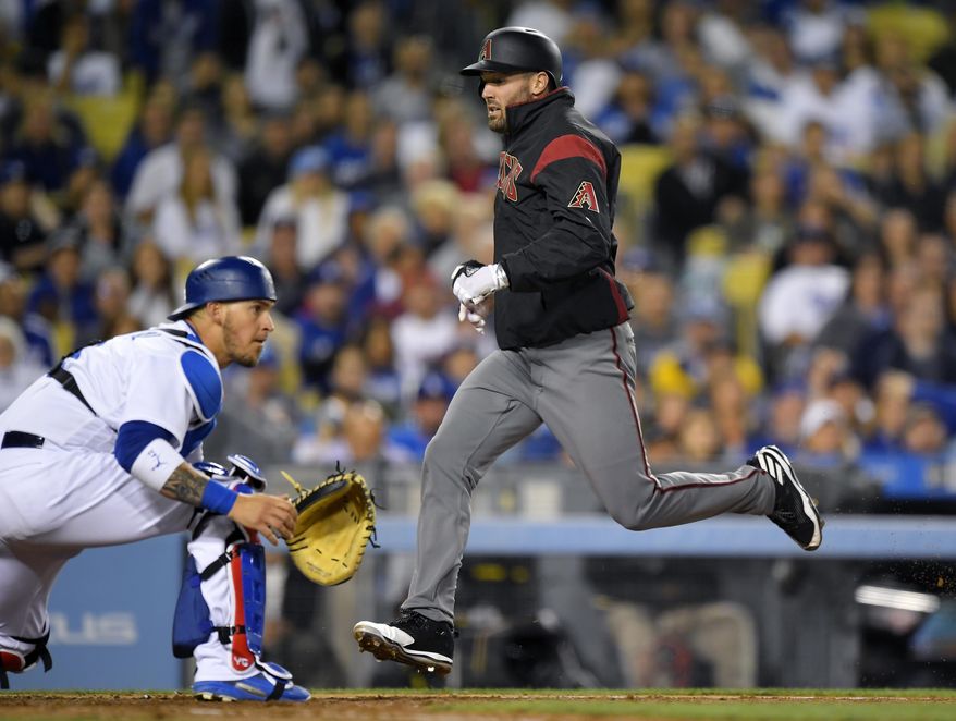 Arizona Diamondbacks' Robbie Ray, right, scores on a single by David Peralta as Los Angeles Dodgers catcher Yasmani Grandal takes a late throw during the fifth inning of a baseball game, Monday, April 17, 2017, in Los Angeles. (AP Photo/Mark J. Terrill)