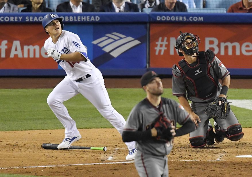 Los Angeles Dodgers' Enrique Hernandez, left, hits a solo home run as Arizona Diamondbacks starting pitcher Robbie Ray, center, and catcher Jeff Mathis watch during the fourth inning of a baseball game, Monday, April 17, 2017, in Los Angeles. (AP Photo/Mark J. Terrill)