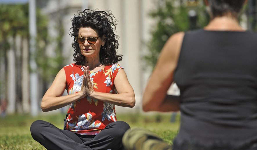 In this April 7, 2017. photo, County Court Judge Eleni Derke leads her yoga class on the lawn outside the Duval County Courthouse in Jacksonville, Fla. Derke is a certified yoga instructor. Derke holds her Yoga on the Lawn class once a month until the weather gets too hot. (Bob Self/The Florida Times-Union via AP)