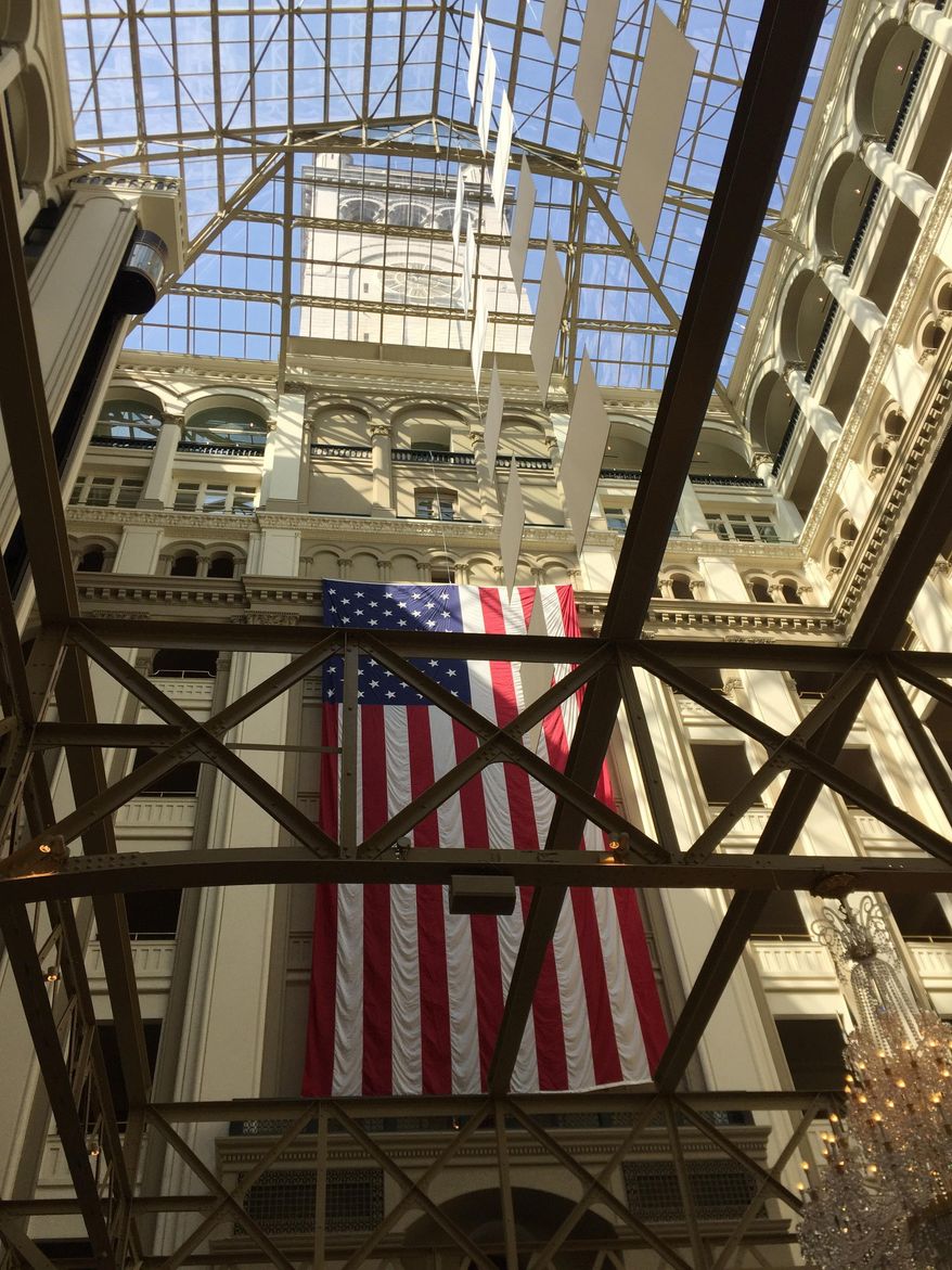 This April 13, 2017 photo shows The Old Post Office clock tower in Washington, D.C., photographed through metalwork that was part of mail-sorting equipment and a glass atrium from the lobby of the Trump International Hotel. The adjacent clock tower is operated by the National Park Service and was recently reopened to the public for tours. (AP Photos/Beth J. Harpaz)