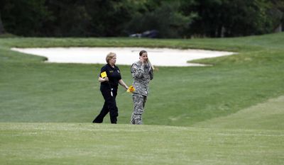 Investigators walk on a golf course as they examine debris that fell at the Breton Bay Golf and Country Club when an Army UH-60 helicopter from Fort Belvoir, Va., crashed, Monday, April 17, 2017, in Leonardtown, Md. (AP Photo/Alex Brandon)