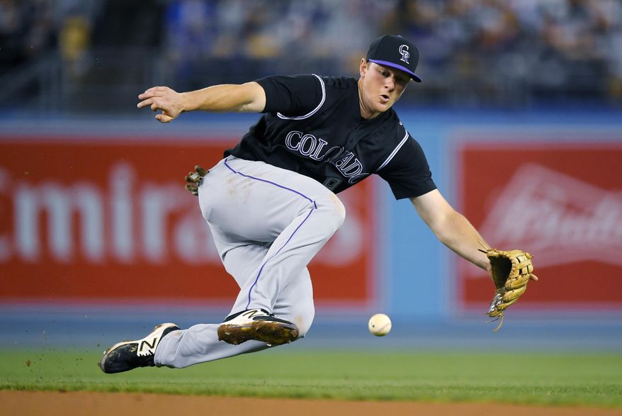 Colorado Rockies second baseman DJ LeMahieu fields a ball hit by Los Angeles Dodgers' Yasiel Puig during the seventh inning of a baseball game, Tuesday, April 18, 2017, in Los Angeles. Puig was safe at first on the play. (AP Photo/Mark J. Terrill)