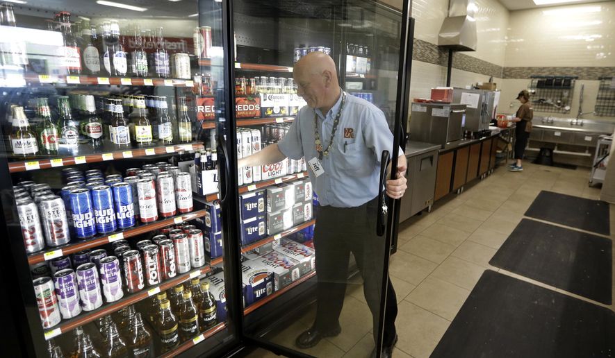 Jeff Williams checks the stock in the beer cooler behind the counter in a Ricker's convenience store in Sheridan, Ind., Wednesday, April 19, 2017. The location is one of two that one gas station owner discovered a loophole in the law that allows them to sell cold beer. The location has installed limited seating and sells reheated burritos, landing a restaurant classification and the right to sell cold beer. (AP Photo/Michael Conroy)
