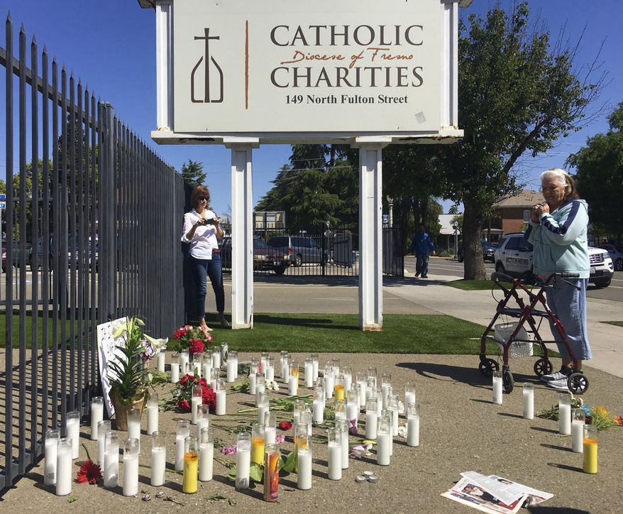 Phyllis Cervantes, right, says a prayer for Tuesday's shooting victims at a memorial of candles and flowers outside Catholic Charities on Wednesday, April 19, 2017 in Fresno, Calif. The three men killed Tuesday had no known connection to each other or to the shooter, Kori Ali Muhammad, who is expected to be arraigned Friday. (Carmen George/The Fresno Bee via AP)