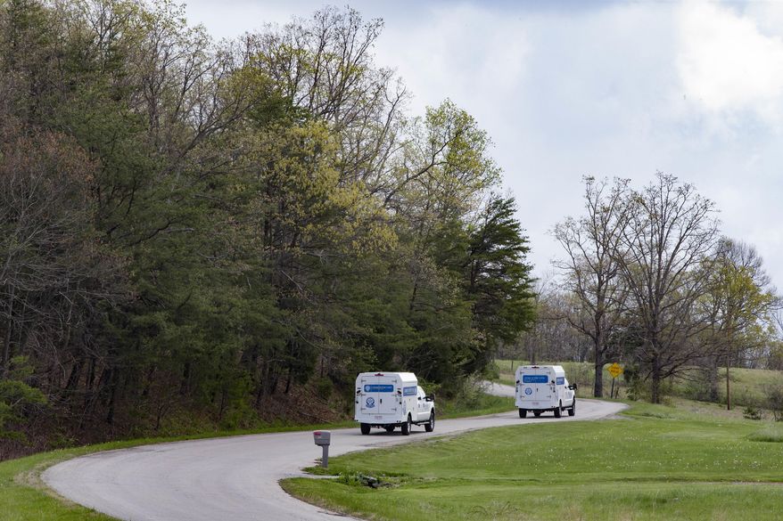FILE – In this April 22, 2016, file photo, crime scene investigation vehicles drive up Union Hill Road after bodies of seven adults and a teenage boy from the Rhoden family were found that day at four homes near Piketon, Ohio. The Ohio Supreme Court on Wednesday, April 19, 2017, ordered the Pike County coroner to submit unredacted autopsy reports from the unsolved slayings for justices to review outside of public view, as the court considers media lawsuits seeking access to those full reports. (AP Photo/John Minchillo, File)