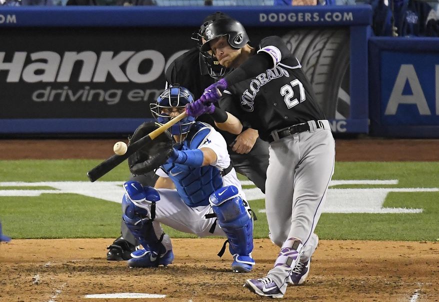 Colorado Rockies' Trevor Story, right, hits a solo home run as Los Angeles Dodgers catcher Austin Barnes watches during the fourth inning of a baseball game, Tuesday, April 18, 2017, in Los Angeles. (AP Photo/Mark J. Terrill)