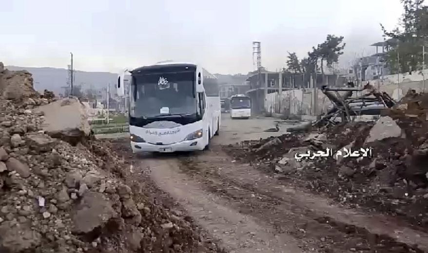 This frame grab from video provided by the government-controlled Syrian Central Military Media, shows buses carrying opposition fighters leaving Zabadani, near Damascus, Syria, Wednesday, April. 19, 2017, heading toward the northern rebel-held Idlib province. Syria's military media says the evacuation and transfer of thousands of Syrians from four besieged areas has resumed. Logo in Arabic reads, "Millitary Media." (Syrian Central Military Media, via AP)