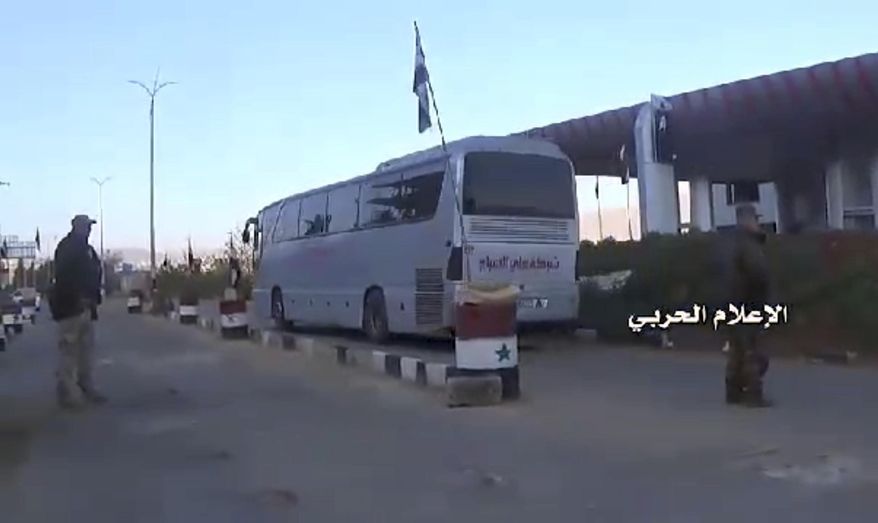 This frame grab from video provided by the government-controlled Syrian Central Military Media, shows buses carrying opposition fighters leaving Zabadani through a checkpoint, near Damascus, Syria, Wednesday, April. 19, 2017, heading toward the northern rebel-held Idlib province. Syria's military media says the evacuation and transfer of thousands of Syrians from four besieged areas has resumed. Logo in Arabic reads, "Millitary Media." (Syrian Central Military Media, via AP)