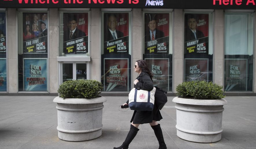 A woman walks past the News Corp. headquarters building displaying posters featuring Fox News Channel personalities including  Bill O&#39;Reilly, top center, in New York, Wednesday, April 19, 2017. (AP Photo/Mary Altaffer)